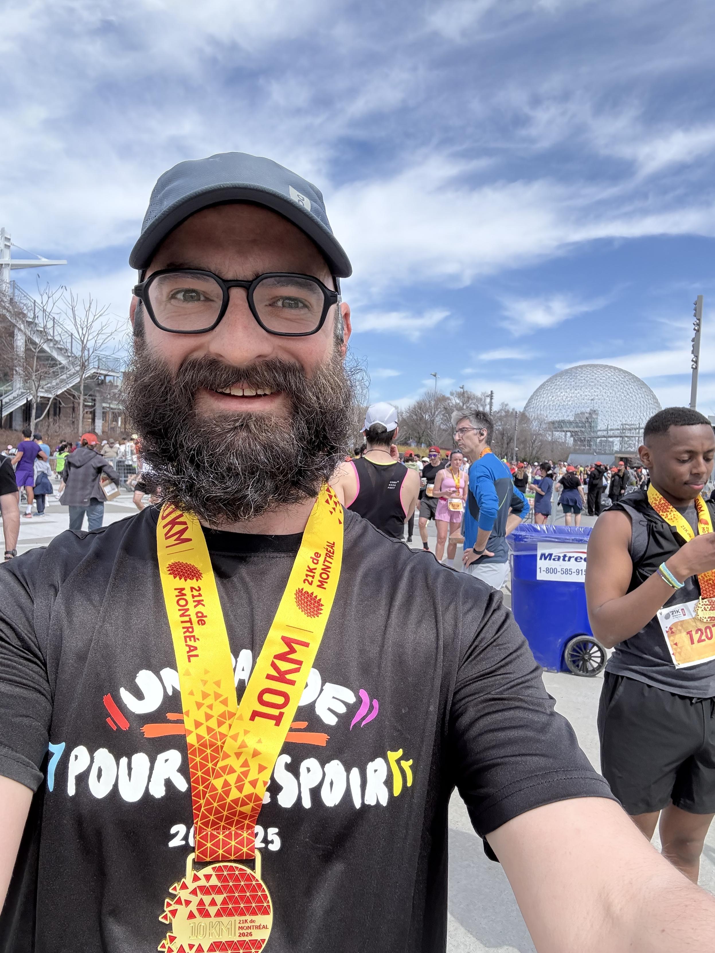 A selfie of me after my race. I have my medal on the neck. Sky is cloudy but nice. We can see the biosphere far in my background.
