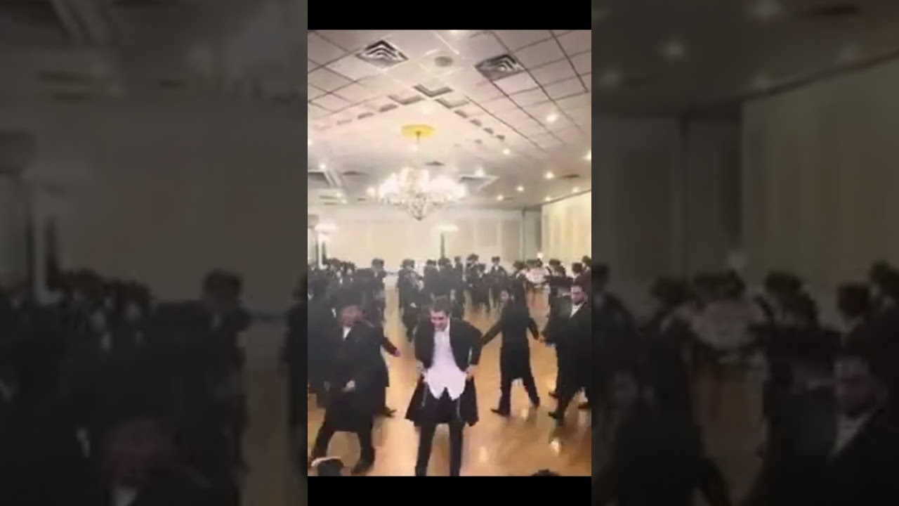 Energetic Dance Party Featuring Men and a Young Boy in Hotel Room..